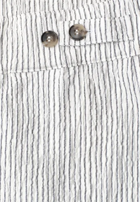 Nahansicht von weißer, gestreifter Stoffhose mit zwei Knöpfen und schmalen schwarzen Längsstreifen.