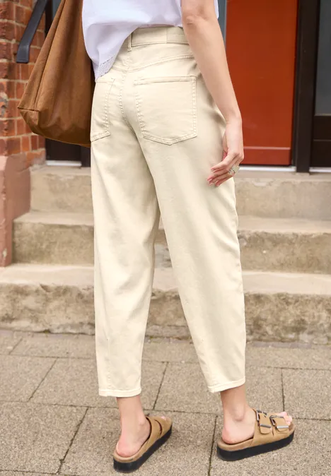 Barrel Leg Jeans im Loose Fit soft ecru Eine Person steht von hinten in hellen, beigen Hosen und Sandalen auf einem Gehweg vor einer Treppe.