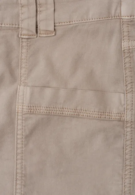 Gros plan d’une poche en tissu beige aux coutures apparentes sur un pantalon.