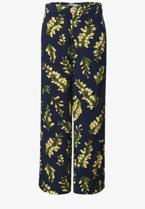 Pantalon large bleu marine à motifs de fleurs jaunes et feuilles vertes.