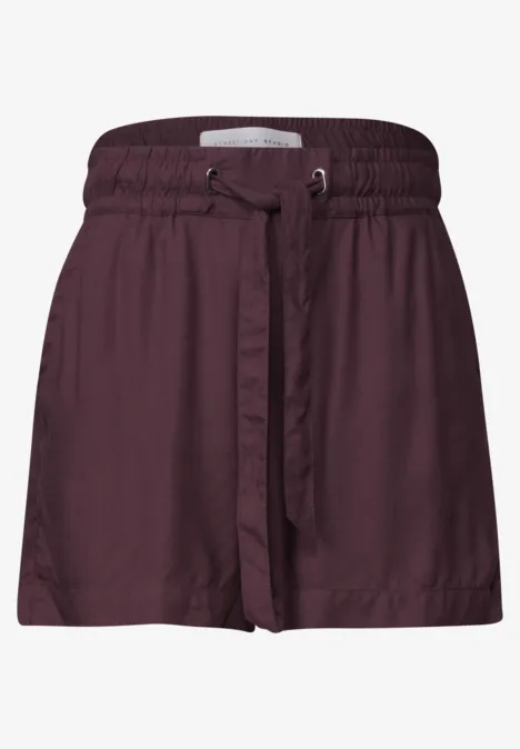 Een korte wijde short in bordeauxrood met elastische tailleband en bijpassende ceintuur