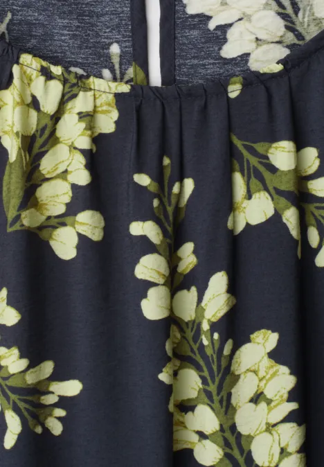 Dunkelblauer Stoff mit gelb-weißen Blumen und grünen Zweigen. Kleidungsdetail.