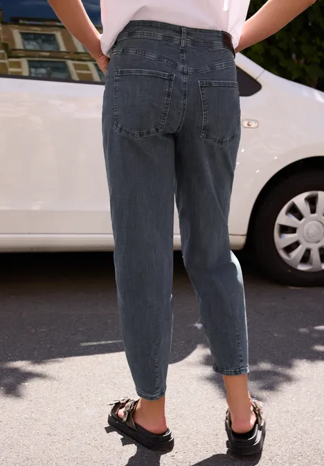 High Waist Barrel Leg Jeans im Loose Fit steel grey net washed Person von hinten in grauen, hochgeschnittenen Jeans und schwarzen Sandalen, stehend vor einem Auto.