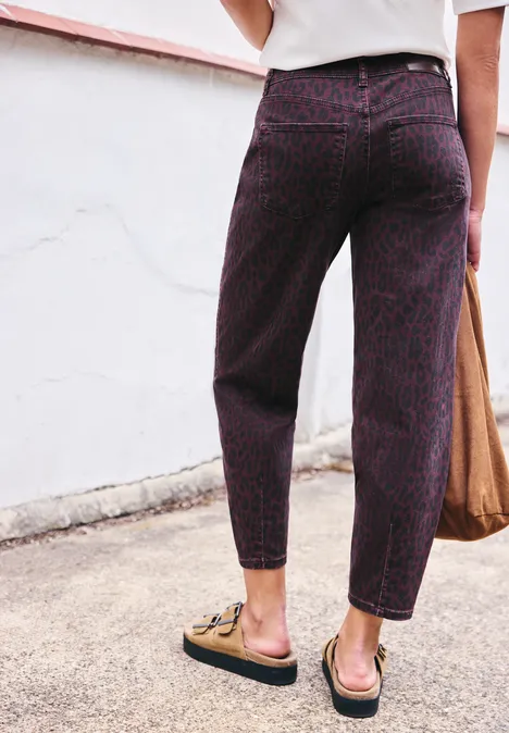 High Waist Barrel Leg Jeans mit Leo-Print burgundi printed wash Person rücklings in gemusterten, hochgeschnittenen, dunkelroten Hosen mit Mules und Stofftasche.