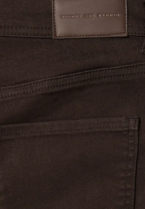 Close-up van een bruine spijkerbroek met achterzak en leren label