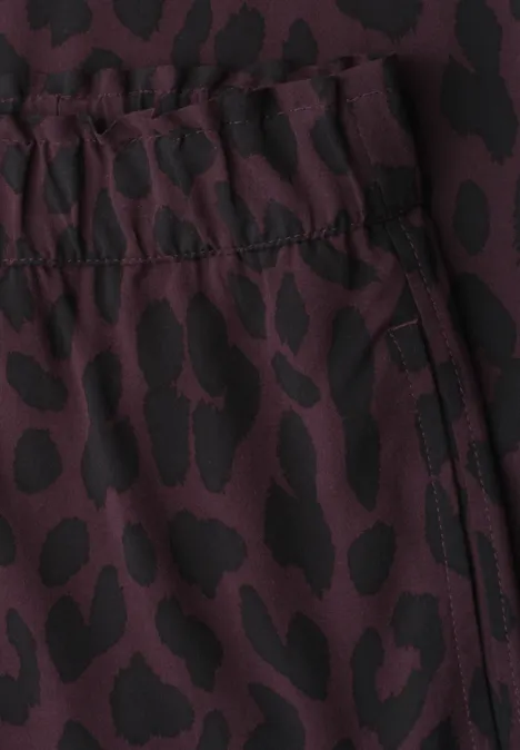 Vêtement bordeaux à taille élastiquée, motif léopard noir et poche zippée.