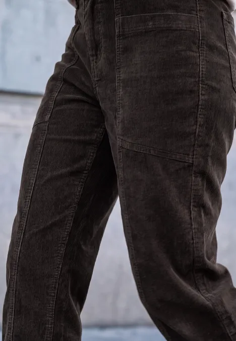 Dunkelbraune Cordhose, Nahaufnahme der Hosenbeine vor einer Betonwand.