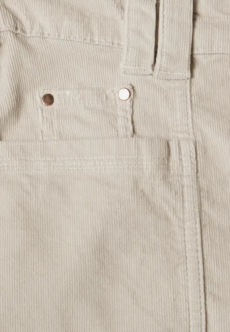 Gros plan d’un pantalon en velours côtelé beige avec poche avant et rivet métal