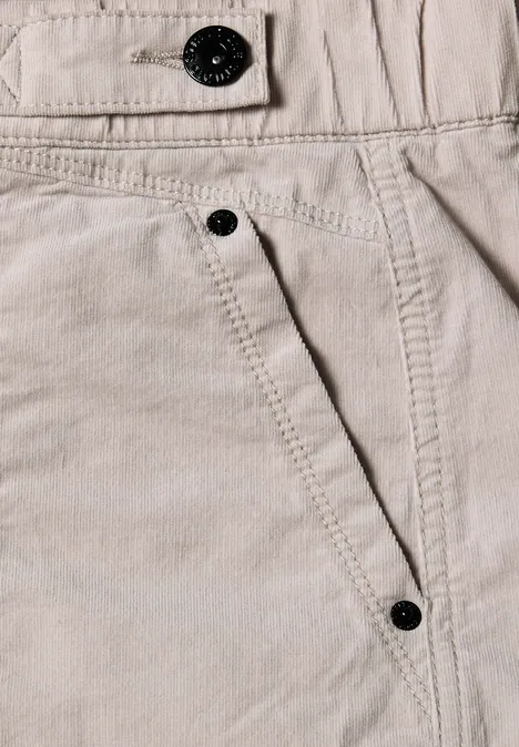 Nahaufnahme einer hellbeigen Hose aus Baumwolle mit sichtbarer Naht und schwarzen Knöpfen.