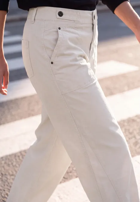 Eine Person trägt helle, weite Hose beim Überqueren einer Straße mit Zebrastreifen.