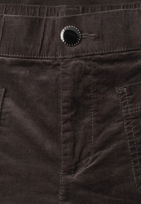 Nahaufnahme einer dunkelbraunen Cordhose mit Bund, Gürtelschlaufen und Knopfdetail.