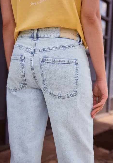Person von hinten in hellblauen Jeans und gelbem Top, im urbanen Umfeld