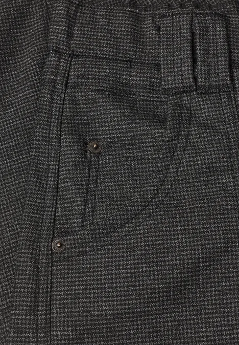 Detail einer grauen, karierten Hose mit Gummibund und seitlicher Tasche mit Ziernaht.
