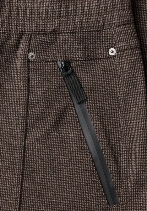 Braune karierte Stoffhose mit diagonaler, schwarzer Reißverschlusstasche und silbernen Nieten