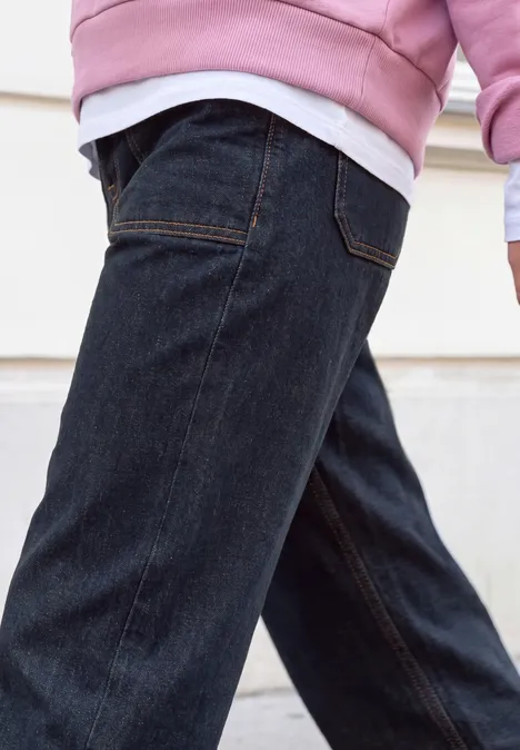 Relaxed Barrel Leg Leg Jeans im Loose Fit rinse washed Eine Person in dunklen Jeans mit pinkem Sweatshirt und weißem Shirt darunter.