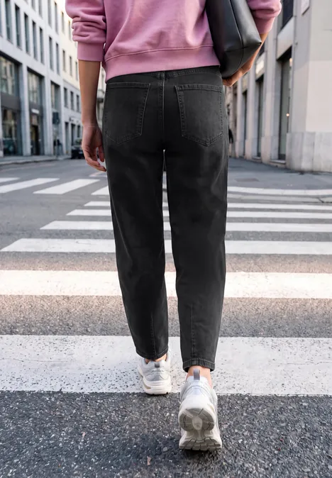 Relaxed Barrel Leg Leg Jeans im Loose Fit soft black washed Person in schwarzen Jeans und weißen Sneakern läuft über einen Zebrastreifen in urbaner Straße.