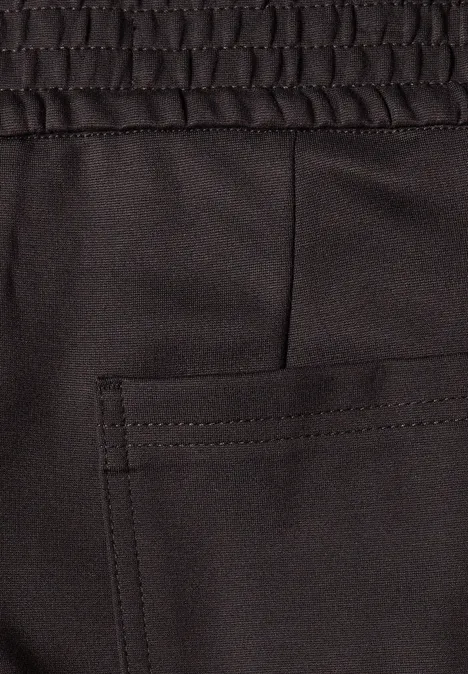 Mid Waist Barrel Leg Hose im Loose Fit charred brown Close-up eines schwarzen Stoffhosenbunds mit elastischem Saum und aufgesetzter Tasche