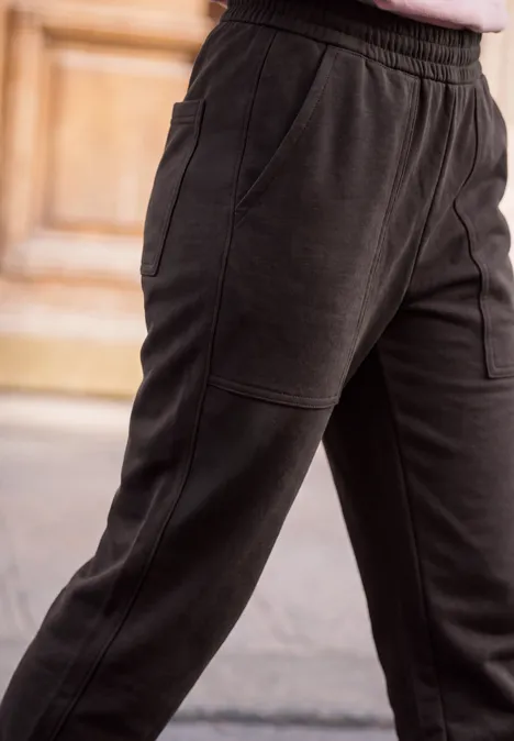 Mid Waist Barrel Leg Hose im Loose Fit charred brown Schwarze, lockere Jogginghose mit seitlichen Eingrifftaschen an einer Person.