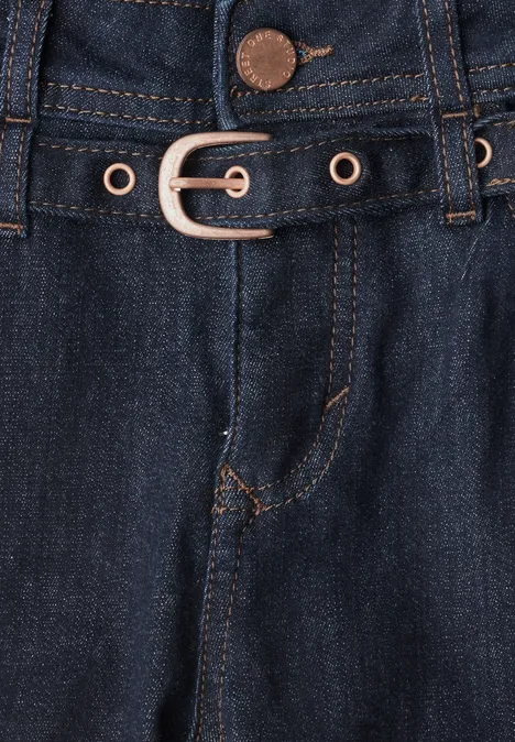 Gros plan sur un jean bleu foncé avec ceinture et œillets métalliques.