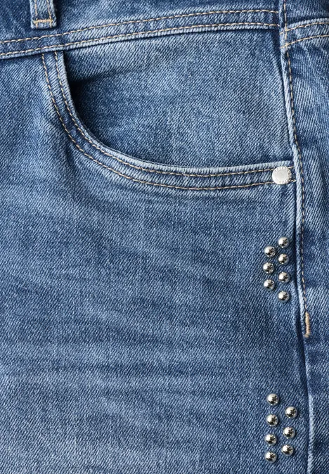Close-up van een blauwe spijkerbroek met zak, lus en zilverkleurige studs.