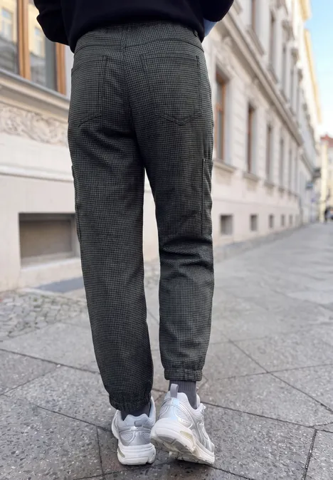 Vue de dos d'une personne en pantalon de jogging gris et baskets blanches marchant sur un trottoir pavé.