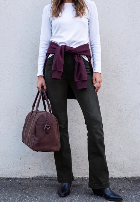 Wit shirt met lange mouwen, olijfgroene broek, zwarte laarzen, bordeaux trui om de taille geknoopt, bijpassende tas.