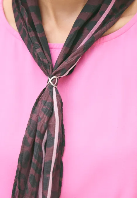 Gemusterter schwarzer-rosa Schal in Ringknoten über pinkem Shirt.