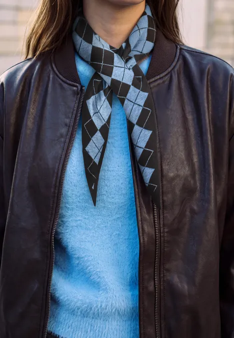 Foulard triangulaire à motif Argyle loom blue Schwarze Lederjacke über hellblauem Pullover, diamond-muster Halstuch in Schwarz und Hellblau.