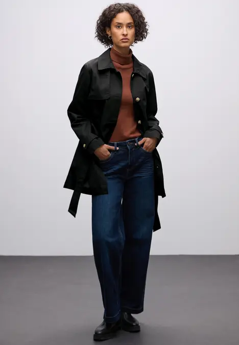 Frau in schwarzem Mantel mit Tasche.