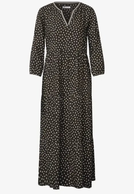 Robe longue noire à pois blancs, col en V, manches longues et coupe fluide.