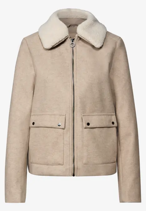 Beige Jacke mit Fellkragen, Reißverschluss und großen Taschen.