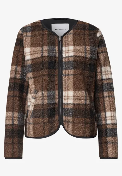 Veste à carreaux marron, noir et blanc, sans col, fermeture éclair et manches longues.