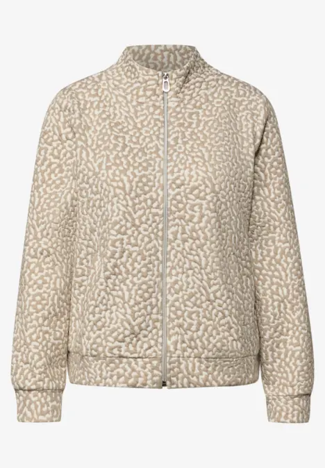 Hellbeige Bomberjacke mit weißem abstraktem Muster, durchgehendem Reißverschluss und Rippstrickbündchen.