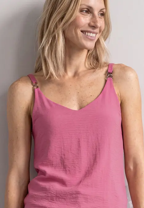 Lächelnde Frau mit blonden Haaren trägt rosa Top mit Spaghettiträgern
