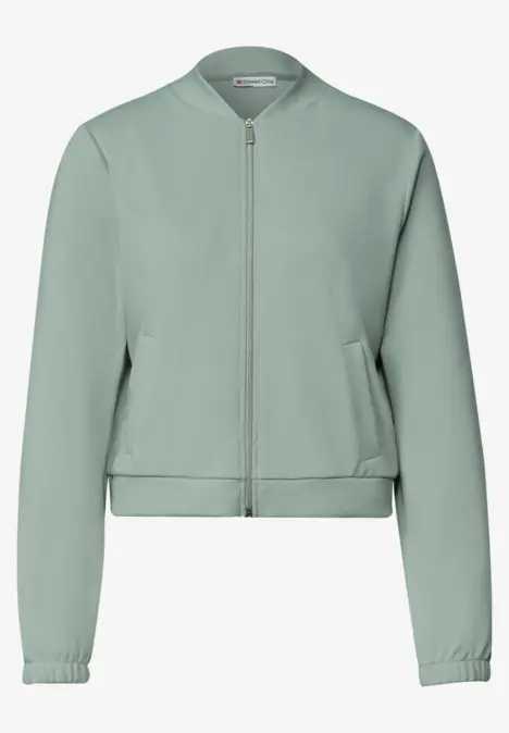 Blouson bomber vert clair avec fermeture éclair, manches longues et poches latérales.
