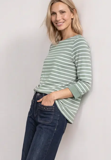 Frau mit grün-weiß gestreiftem Pullover und Jeans, lächelnd