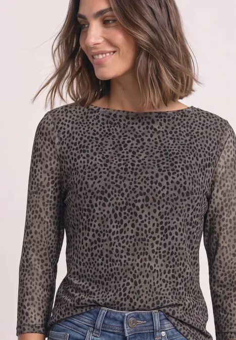 Vrouw met glimlach draagt een aansluitend olijfgroen shirt met lange mouwen en fijn zwart luipaardpatroon.