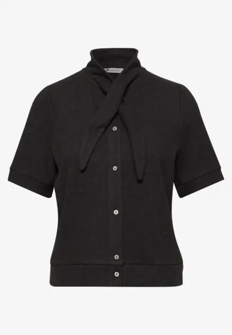 Schwarze Strickbluse mit kurzen Ärmeln, Knopfleiste und angenähter Bändchenschleife am Kragen.