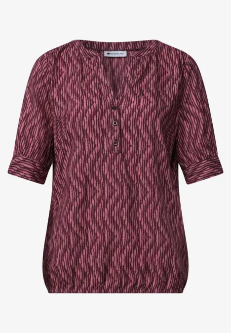 Rosa-schwarze, kurzärmelige Damenbluse mit V-Ausschnitt und Zickzackmuster.