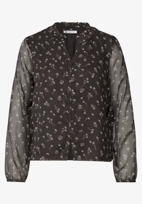 Schwarze Bluse mit Knöpfen, kleinen weißen Blumen und transparenten langen Ärmeln.