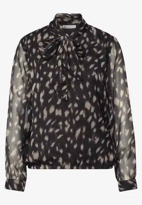 Blouse noire transparente à motifs léopard discrets et col noué.