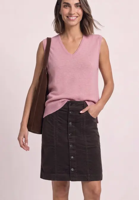 Vrouw draagt roze mouwloos V-hals top, donker knielang knooprokje en een bruine tas.