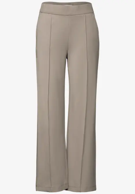 Beige Stoffhose mit weitem Bein und Bügelfalten.