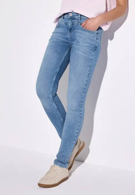 Person trägt hellblaue Skinny-Jeans und helle Sneaker.