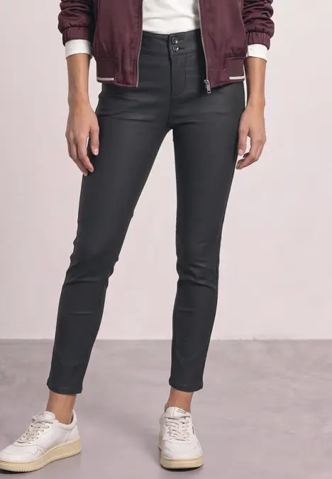 Schlanke schwarze beschichtete Jeans mit hohem Bund, legerem Umschlag am Knöchel und weißen Sneakers.