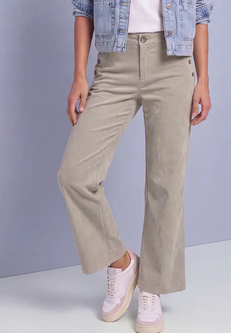 Beige weite Cordhose im 70er-Stil mit ausgestelltem Bein, kombiniert mit weißen Sneakern.