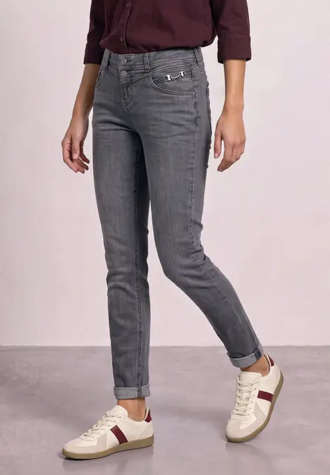 Graue Jeans kombiniert mit weißen Sneakers und einem burgunderfarbenen Oberteil.