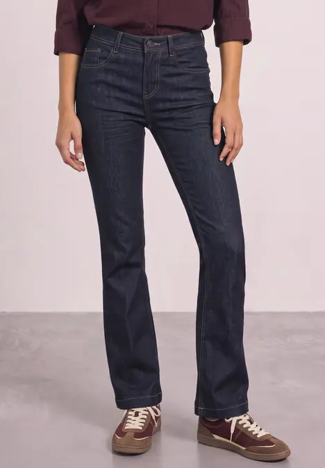 Hohe, dunkelblaue Jeans mit leicht ausgestelltem Bein, kombiniert mit Hemd und Sneakern.