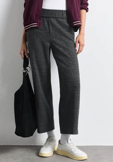 Graue Bügelfaltenhose im Karomuster, weiße Sneakers und schwarze Stofftasche, legerer Streetstyle.