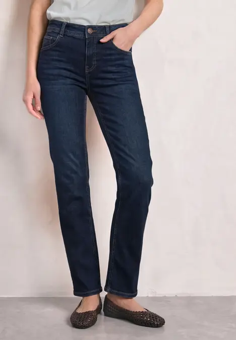 Eine Person trägt dunkelblaue, gerade geschnittene Jeans mit schwarzen Ballerinas.
